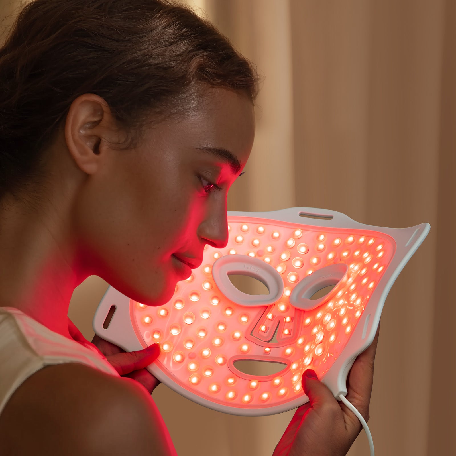 Model using LED red light therapy face mask at home