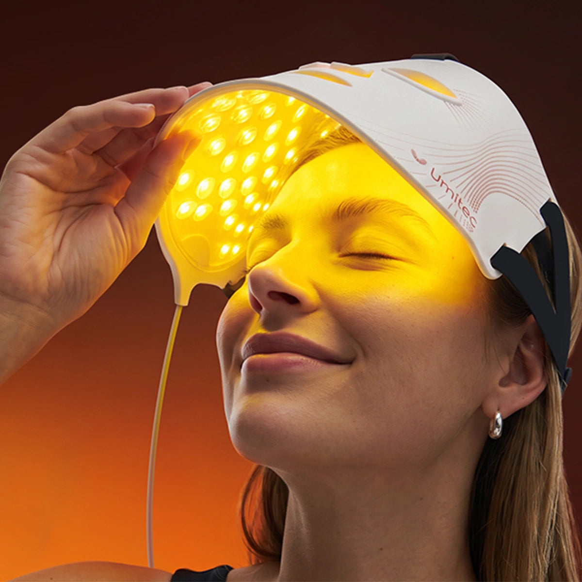 A women is putting the white Umitec LED Face Mask onto her face